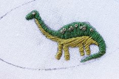 a close up of a embroidered dinosaur on a white shirt