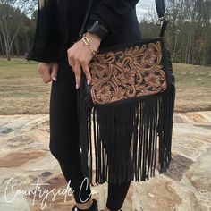 "A work of art in tooled leather, Rio Grande's Western-inspired design culminates in a masterpiece; lavishly finished with fringed edges and adorned with a detachable adjustable strap, this purse presents the perfect combination of sophisticated finish and statement style. Boasting an extra-roomy 7\" x 10\" size and a black leather back with a zipper pocket for added storage, this designer bag carries you through your days and nights. Please note that every purse will be one of a kind as each new purse will be made with a unique new cowhide. If you would like to pick your hide please send a message. Please go to About > Frequently Asked Questions To learn more about the terms of your purchase." Luxury Leather Western Style Shoulder Bag, Western Bags Purses, Leather Hand Tooled Shoulder Bag For Western-themed Events, Western Bags, Western Purses With Fringe, Cowhide Purse With Fringe, Western-themed Brown Leather Shoulder Bag, Western Bag, Tooled Leather Purse