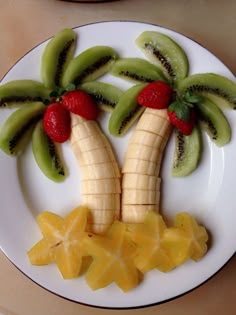 a white plate topped with cut up fruit and palm trees on top of each other