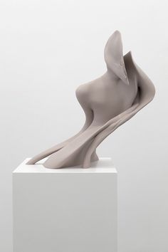 an abstract sculpture is displayed on a white pedestal