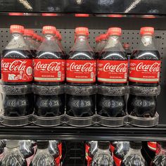 several bottles of coca - cola are on display in a grocery store shelf with other sodas