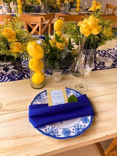 the table is set with yellow flowers and blue place settings for an elegant dinner party