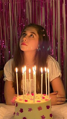 a woman sitting in front of a cake with candles on it