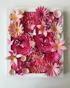 pink paper flowers are arranged in a square frame