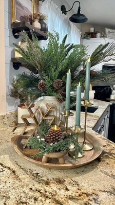 a candle holder with pine cones and greenery in it sitting on a kitchen counter