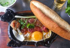 an egg, meat and bread dish on a black plate