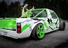 two men standing in the back of a green and white truck with camouflage paint on it