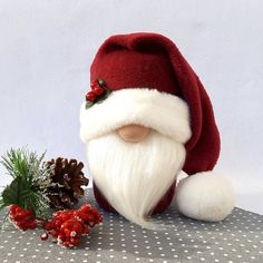 a santa claus doll sitting next to a pine cone