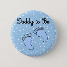 a button with the words daddy to be written on it and two feet in blue