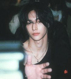 a young man with black hair and piercings holding his hand out to the side