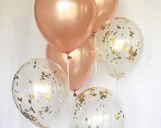 gold and white balloons with confetti on them are arranged in a row against a white background