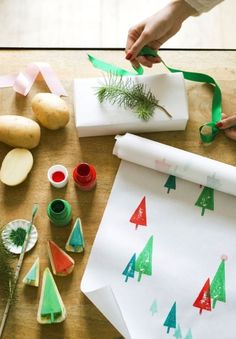 someone is making christmas trees out of wrapping paper and other crafting supplies on a table