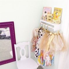 a white chair sitting in front of a mirror next to a shelf with clothes on it