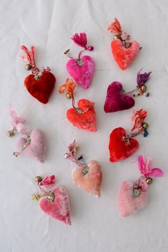 several heart shaped brooches are arranged on a white surface with pearls and beads