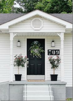 a white house with black front door and two planters