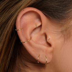 a woman's ear with three thin gold hoops