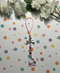 a hello kitty keychain hanging from a pink ribbon