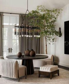 a dining room table with chairs and a potted plant in the center, next to a chandelier