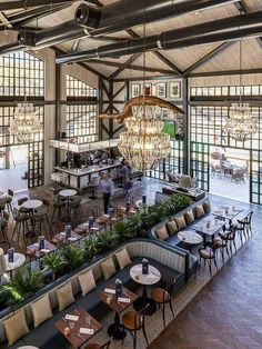 the inside of a restaurant with lots of tables and chairs, chandeliers hanging from the ceiling