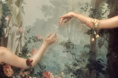 two hands reaching out towards each other in front of a painting with trees and flowers