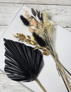 two black and gold fan shaped flowers on top of a white card