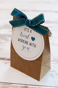 a brown paper bag with a blue ribbon on it that says it's a treat working with you