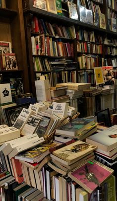 many books are stacked on top of each other in front of a bookcase full of books