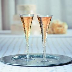 two champagne glasses sitting on top of a silver tray