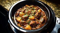 a bowl filled with meat and potatoes on top of a stove