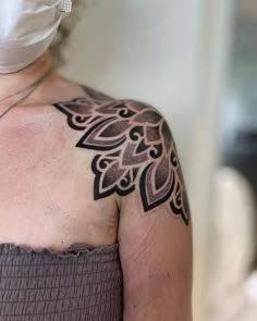 a woman with a tattoo on her upper arm and shoulder is wearing a face mask