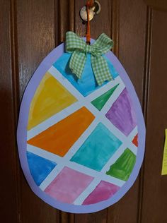 an easter egg painted with colored paper and a green bow hanging on the front door