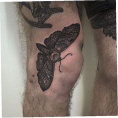 a man's leg with a moth tattoo on it