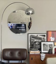 a living room with a chair and a round mirror on the wall