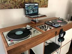 a laptop computer sitting on top of a wooden table next to a dj's turntable