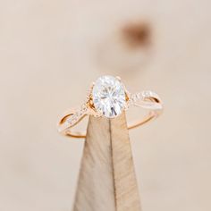 a diamond ring on top of a wooden stand