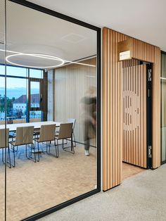 an office meeting room with glass walls and wooden paneling on the wall, along with large sliding doors