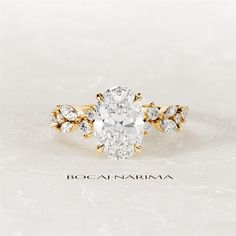 an oval cut diamond ring with leaves on the band, set in 18k yellow gold