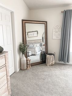 a mirror sitting on top of a wooden dresser next to a bed in a bedroom