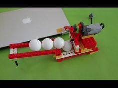 an apple laptop computer sitting on top of a table next to legos and balls