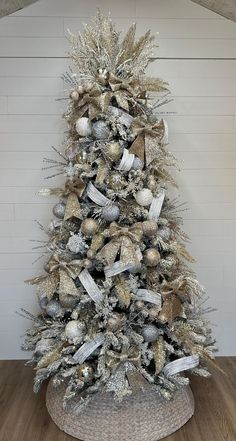 a silver and gold christmas tree with ornaments on it's base in a room