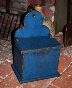 a blue wooden box sitting on top of a red tile floor next to a brick wall