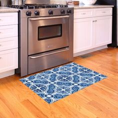 a kitchen with an oven, dishwasher and rug on the wood flooring