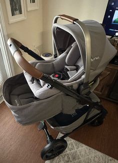 a baby stroller sitting on top of a hard wood floor next to a window