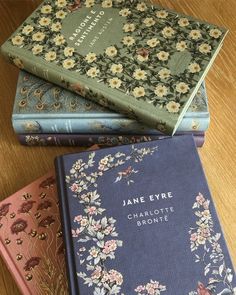 three books sitting on top of a wooden table next to each other with floral covers