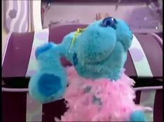 a blue stuffed animal with pink and blue feathers