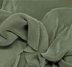 an up close shot of the pleaed fabric on a green bedspread that has been made into a bed cover