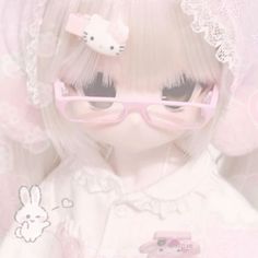 a white doll with pink glasses and a hello kitty hair clip on it's head