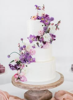 a three tiered cake with purple and white flowers on top