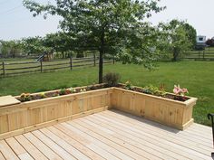 a large wooden planter sitting on top of a wooden deck next to a lush green field