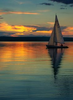 a sailboat floating on top of a lake at sunset